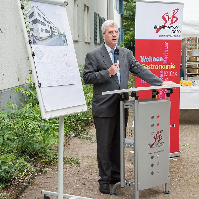 Geschäftsführer mit Mikrofon in der Hand am Rednerpult