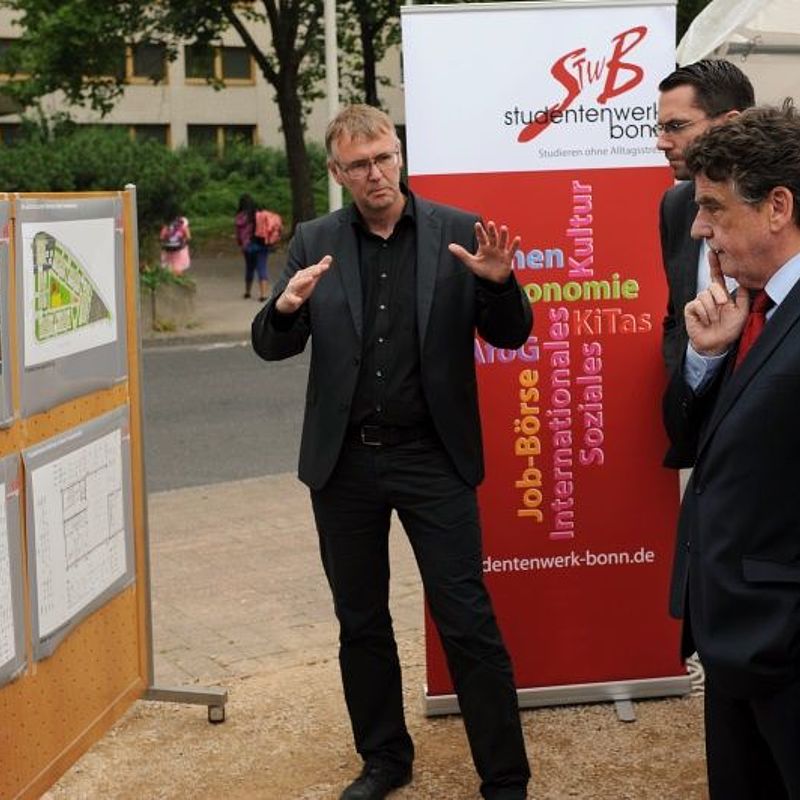 Mann erläutert etwas anhand von Plakaten, die an Pinnwänden hängen.