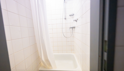 A view inside a shower with white tiles and a shower curtain