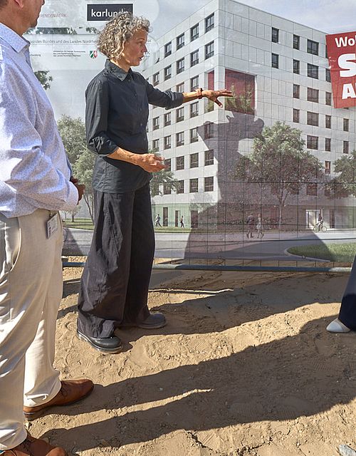 Ministerin Scharrenbach, Oberbürgermeister Deus, die Architektin und Geschäftsführer des Studierendenwerks schauen sich das Banner mit der Visualisierung des Wohnheims an.