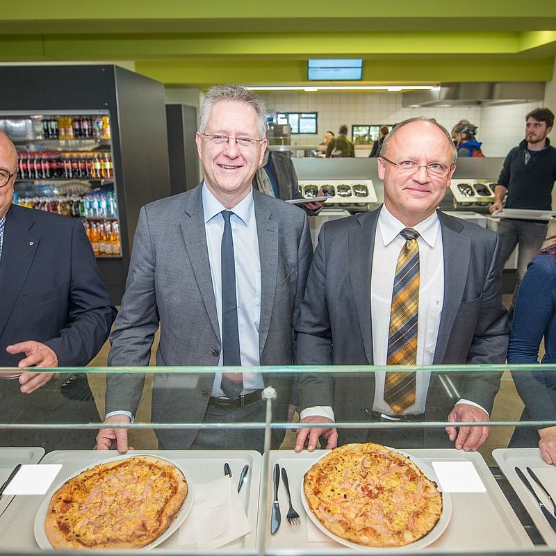 Foto an der Pizzastation bei der CAMPO Eroeffnungmit dem Uni-Rektorm dem Geschäftsführer des Studierendenwerks und der AStA-Vorsitzenden.
