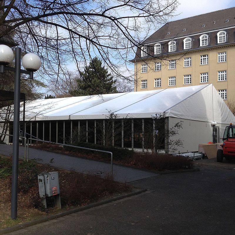 Außenansicht des Speisezeltes, das einen Teil der Ersatzmensa darstellt. Dahinter ein Institutsgebäude der Universität.