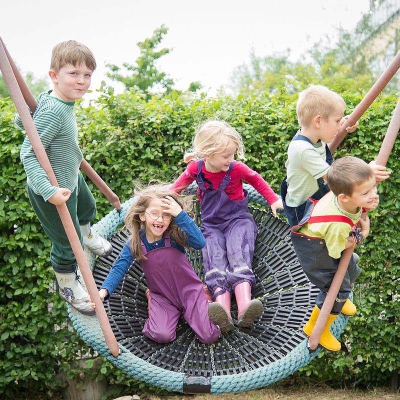 Mehrere Kinder schaukeln in einer großen Netzschaukel